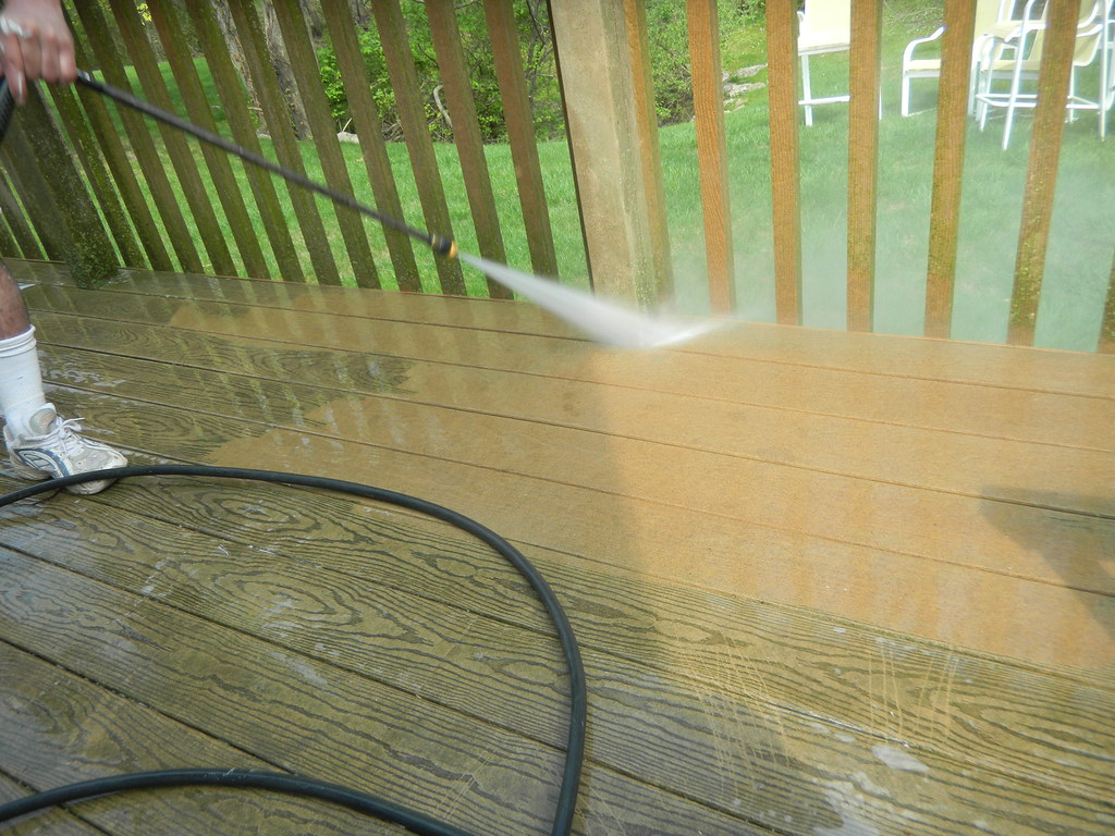 Operator pressure-washing a timber deck in Christchurch, dirty boards turning clean under the fan spray